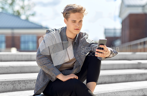 Image of teenage boy using smartphone in city