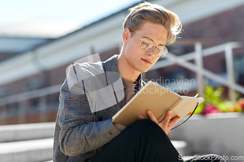 Image of young man with notebook or sketchbook in city