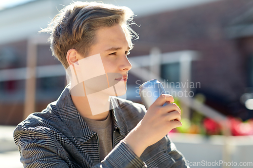 Image of young man with drink in tin can in city