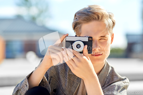 Image of young man with camera photographing in city
