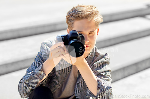 Image of young man with camera photographing in city