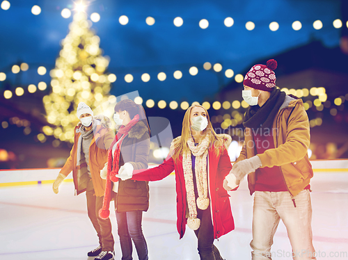 Image of friends in masks at christmas skating rink