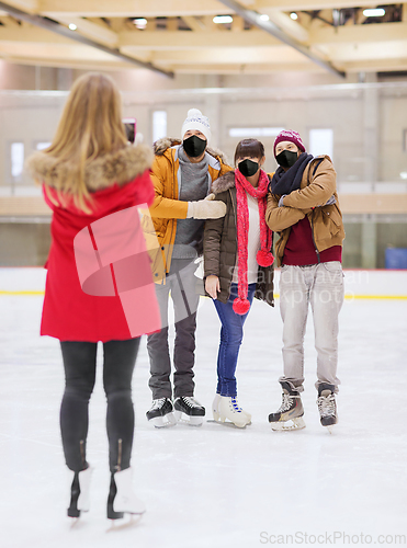 Image of friends in masks taking photo on skating rink