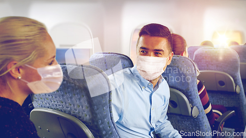 Image of passengers in masks talking in plane