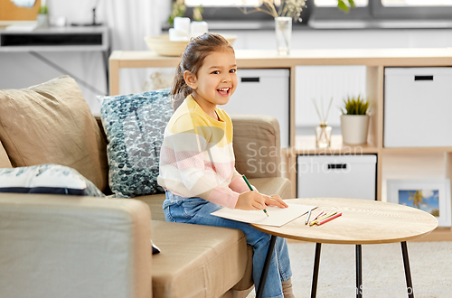 Image of little girl drawing with coloring pencils at home