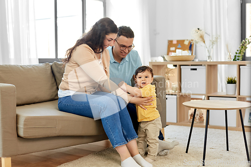 Image of happy family with child sitting on sofa at home