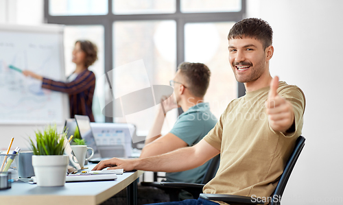 Image of happy man showing thumbs up at office