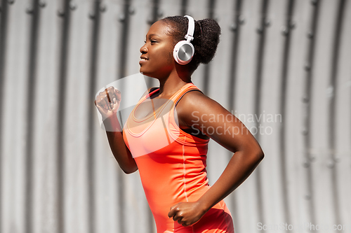 Image of happy african american woman running outdoors