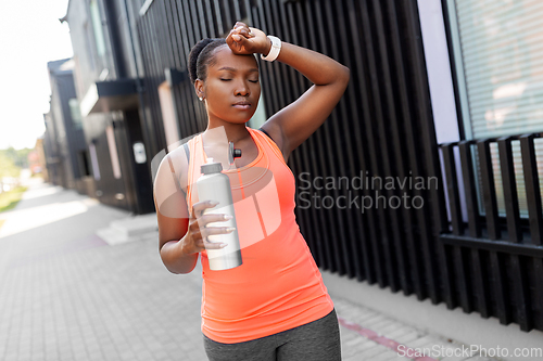 Image of tired african american woman with bottle of water