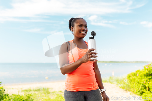 Image of african american woman drinking water after sports