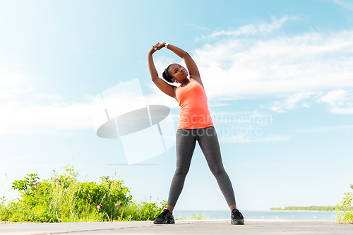 Image of young african american woman exercising on beach