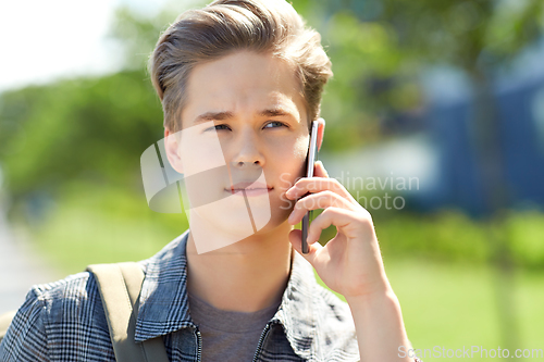 Image of teenage student boy calling on smartphone in city