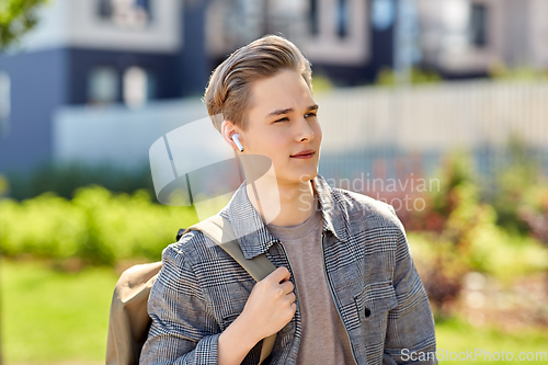 Image of young man with earphones and backpack in city