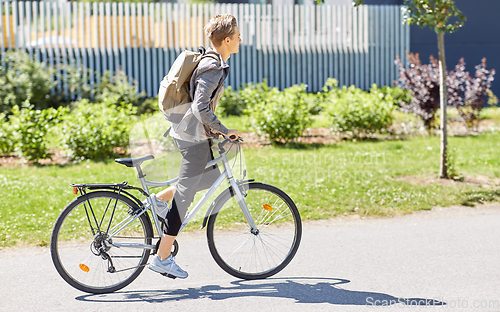 Image of young man riding bicycle on city street