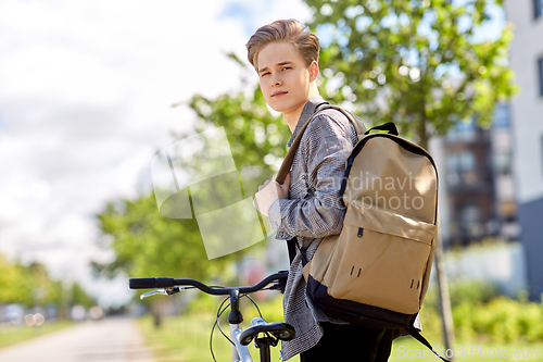 Image of young man with bicycle and backpack on city street
