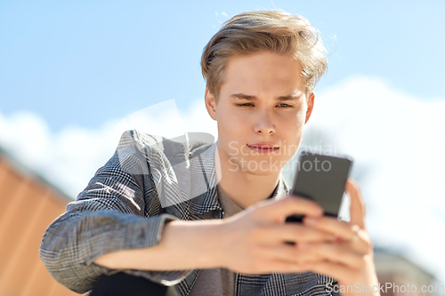 Image of young man or teenage boy using smartphone outdoors