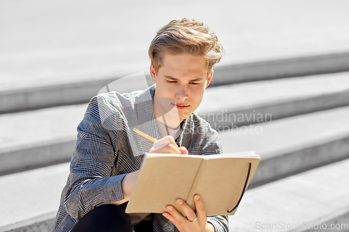 Image of young man with notebook or sketchbook in city