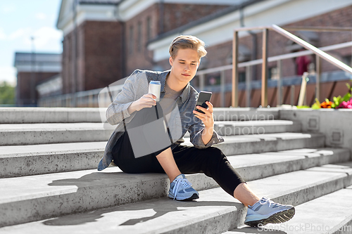 Image of teenage boy with drink and smartphone in city