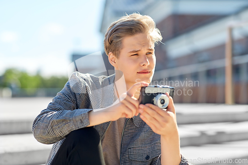 Image of young man with camera photographing in city