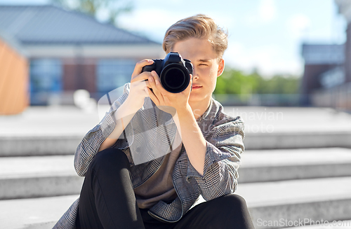 Image of young man with camera photographing in city