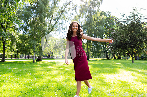 Image of happy smiling woman walking along summer park