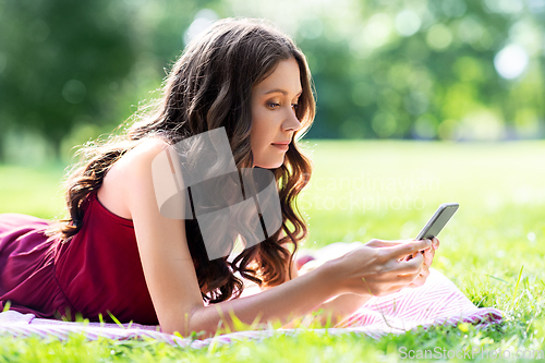 Image of beautiful young woman with smartphone at park