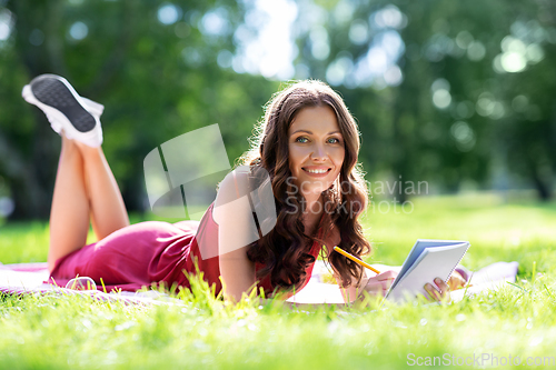 Image of happy woman with diary or notebook at park