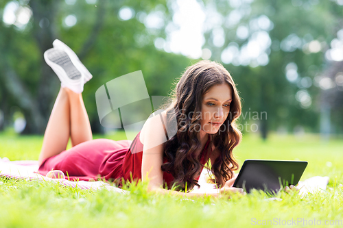 Image of happy woman with tablet computer at park