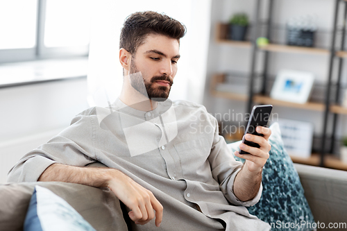 Image of young man with smartphone at home