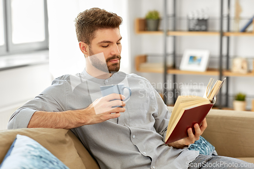 Image of man reading book and drinking coffee at home