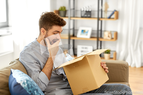 Image of happy surprised man opening parcel box at home