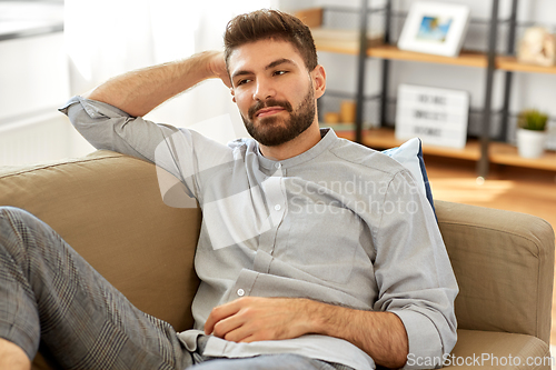 Image of young man sitting on sofa at home