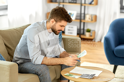 Image of man with money and calculator filling papers