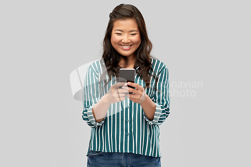 Image of happy asian woman using smartphone