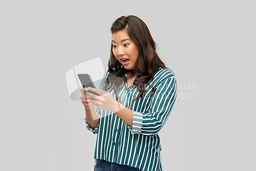 Image of surprised asian woman using smartphone