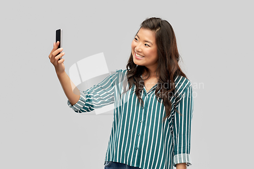 Image of smiling asian woman taking selfie by smartphone