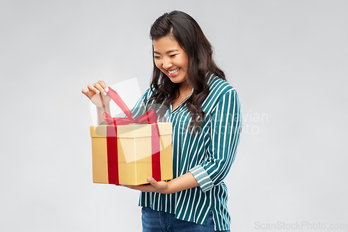 Image of happy asian woman opening gift box