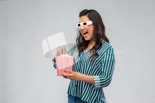 Image of asian woman in 3d movie glasses eating popcorn