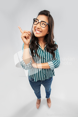 Image of smiling asian student woman pointing finger up