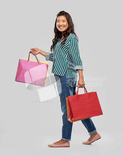 Image of happy asian woman walking with shopping bags