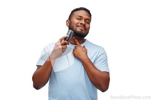 Image of smiling african man shaving beard with trimmer