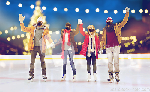 Image of friends in masks waving hands on skating rink