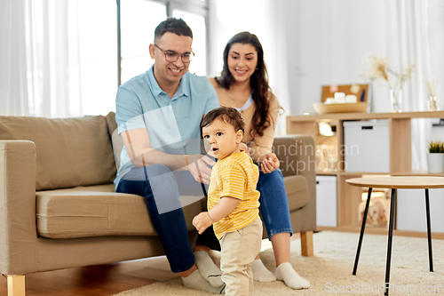 Image of happy family with child sitting on sofa at home
