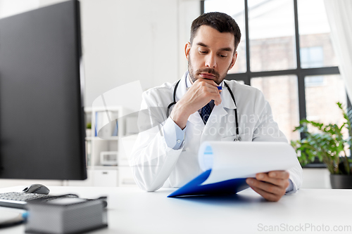 Image of stressed male doctor with clipboard at hospital