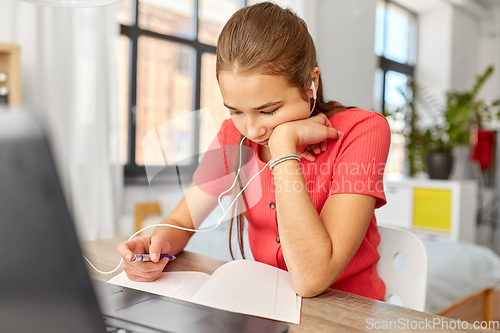 Image of student girl in earphones learning at home