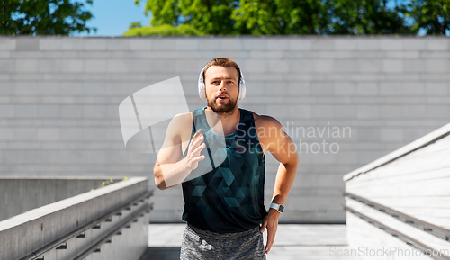 Image of young man in headphones running outdoors