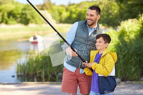 Image of happy smiling father and son fishing on river