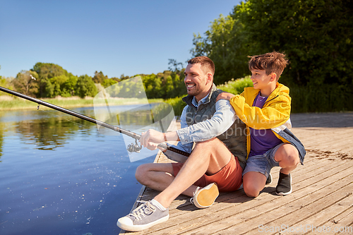 Image of happy smiling father and son fishing on river