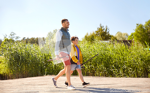 Image of happy smiling father and son fishing on river