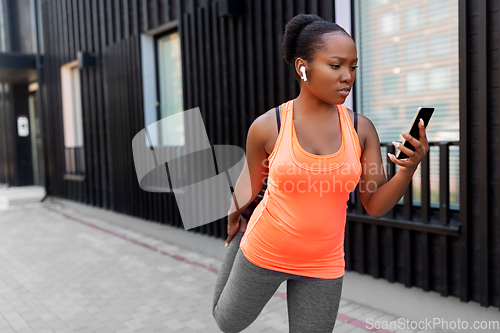 Image of african woman with smartphone exercising outdoors